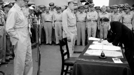 General Douglas MacArthur watches as the foreign minister Manoru Shigemitsu of Japan signs the surrender document ending WW2