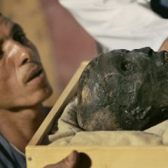 An archaeological worker looks across at the face of the linen-wrapped mummy of King Tut (AP Photo-Ben Curtis, Pool)