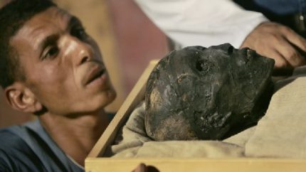 An archaeological worker looks across at the face of the linen-wrapped mummy of King Tut (AP Photo-Ben Curtis, Pool)