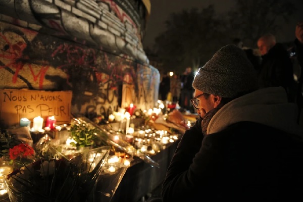 A man pays respect to victims of the attacks next to a sign reading 'We Are Not Afraid' at Place de la Republique (AP Photo-Christophe Ena)