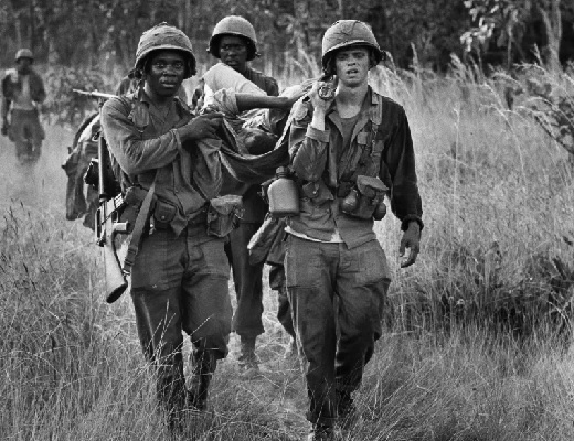 U S cavalrymen carry a wounded soldier to an evacuation zone after a North Vietnamese ambush in la Drang Valley (AP Photo-Peter Arnett)