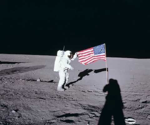 Apollo 12 commander Charles Conrad unfurls the United States flag on the lunar surface during the first extravehicular activity