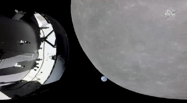 NASA’s Orion capsule, left, nearing the moon, right - At center is Earth (NASA via AP)