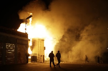 People walk away from a storage facility on fire after the announcement of the grand jury decision (AP Photo-Jeff Roberson)