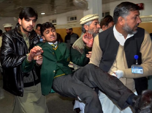 Pakistani volunteers carry a student injured in the shootout at a school under attack by Taliban gunmen, at a local hospital in Peshawar