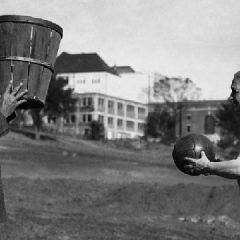 James Naismith holds the basket.