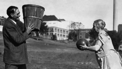 James Naismith holds the basket.