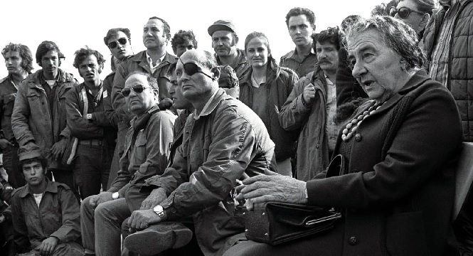  Prime Minister Golda Meir, accompanied by Defense Minister Moshe Dayan, meets with Israeli soldiers at a base on the Golan Heights during the 1973 Yom Kippur War