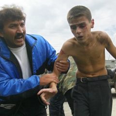 A man helps an injured boy running from a seized school in Beslan, North Ossetia